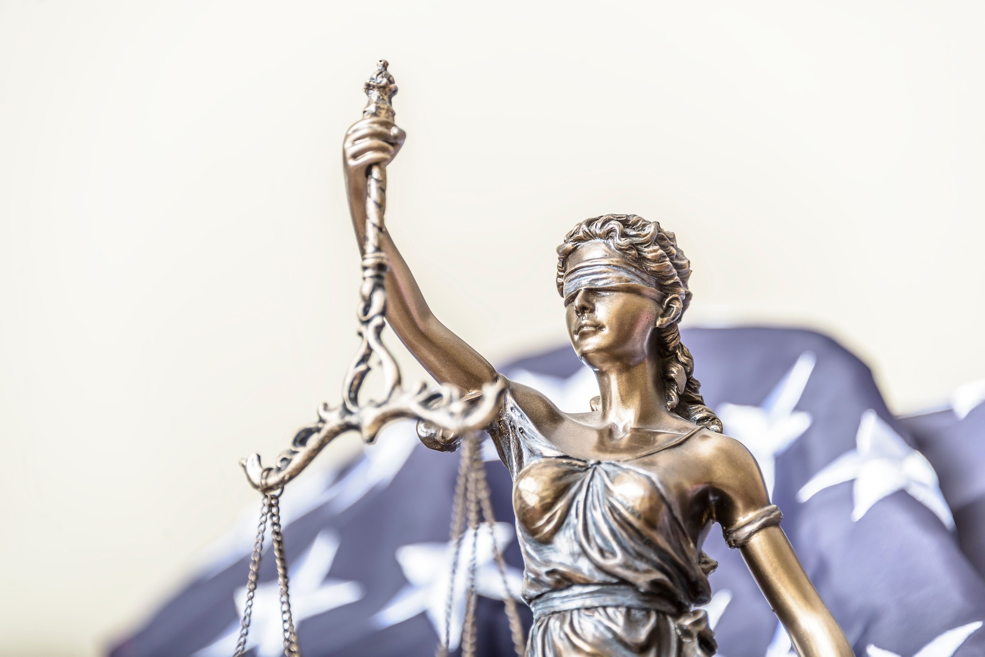 Bronze figurine of Themis holds wedding rings on scales of balance, being in foreground. Couple divorce.