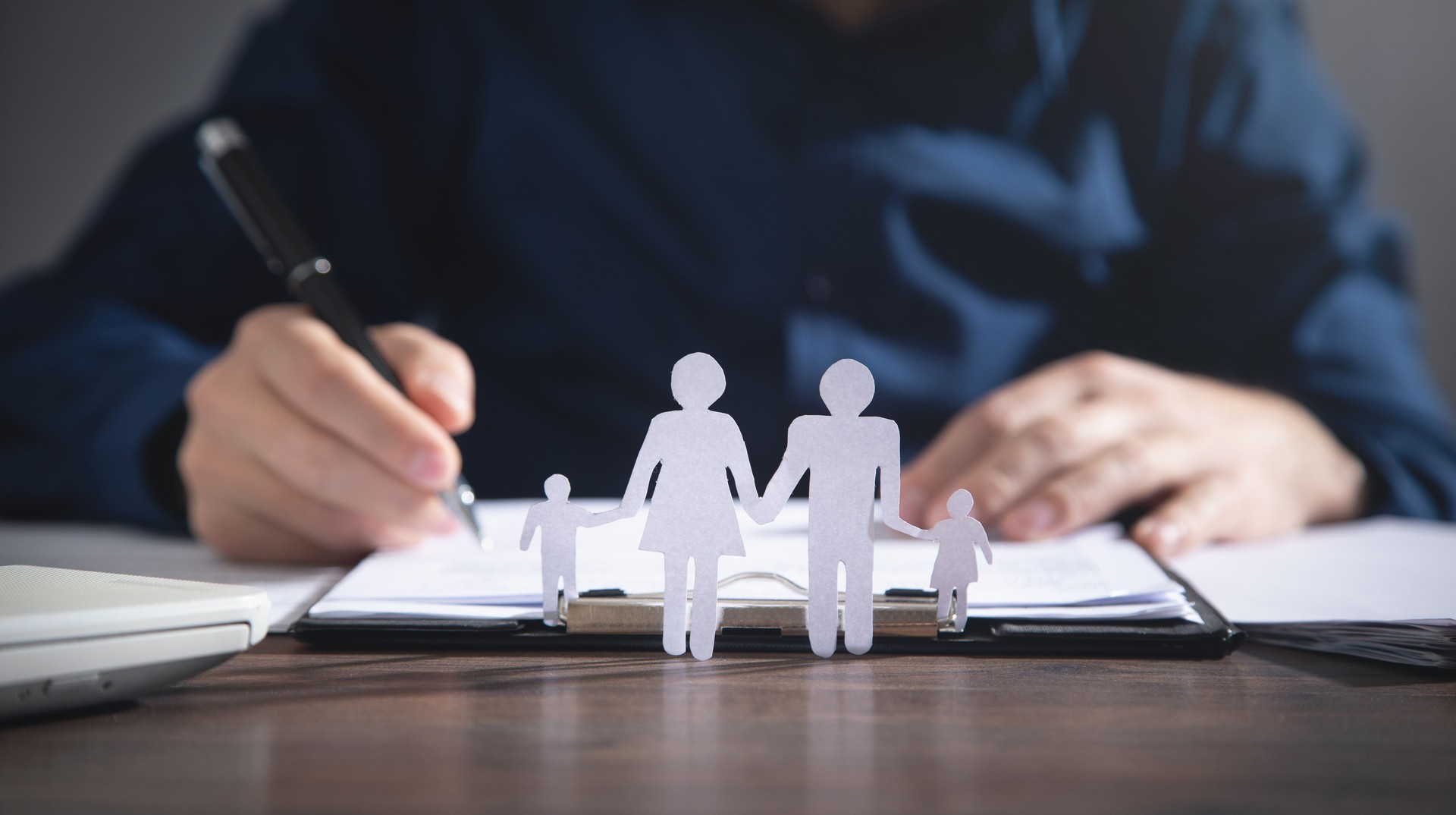 Businessman signing in document. Paper cut family on the desk. Family, Life, Health insurance